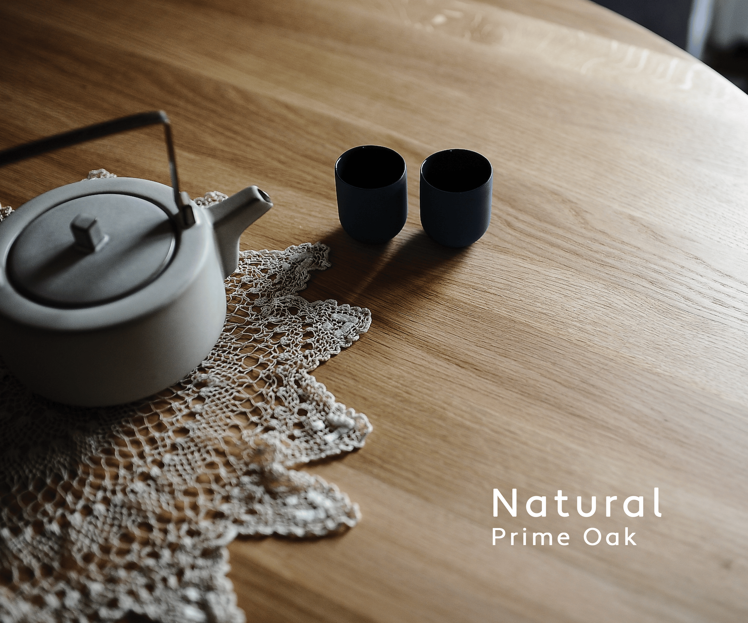 Handcrafted solid prime oak round dining table with smooth tapered legs and natural finish, shown in a bright modern dining space