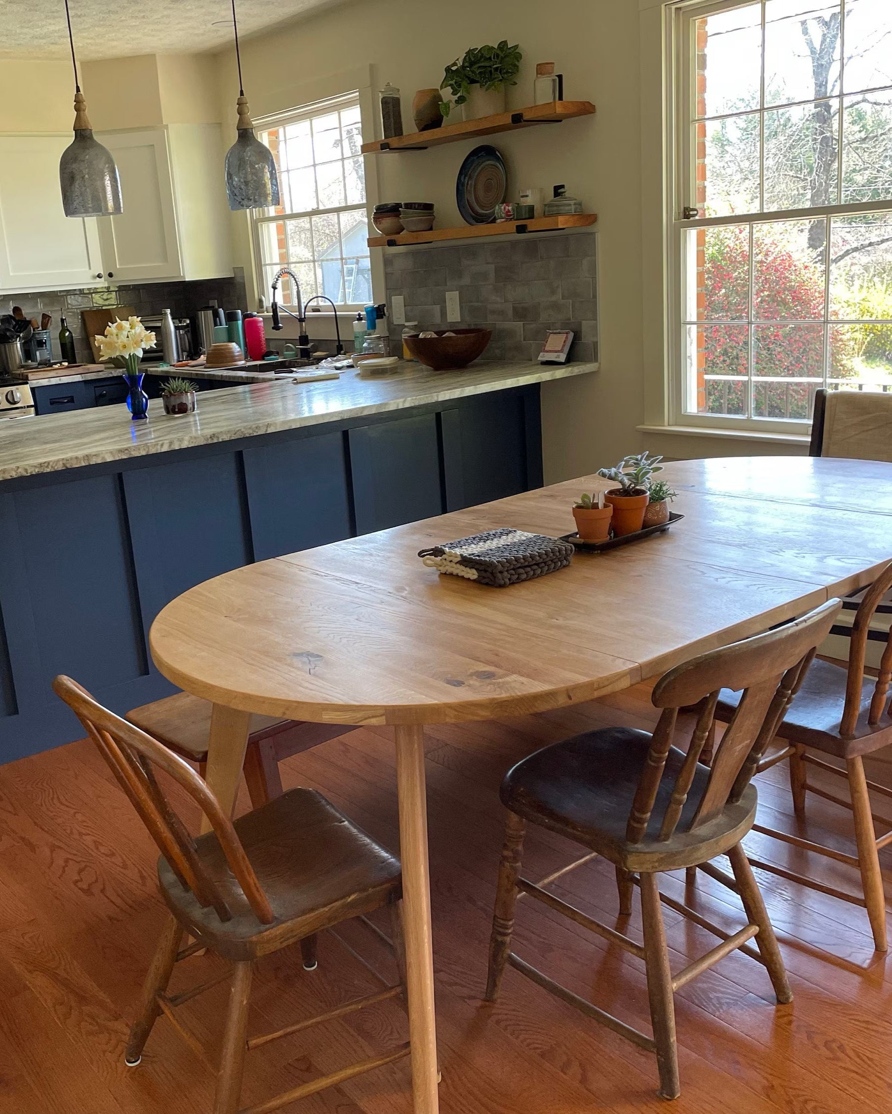 Kitchen with a dining table and chairs, stainless steel appliances, and large windows.
