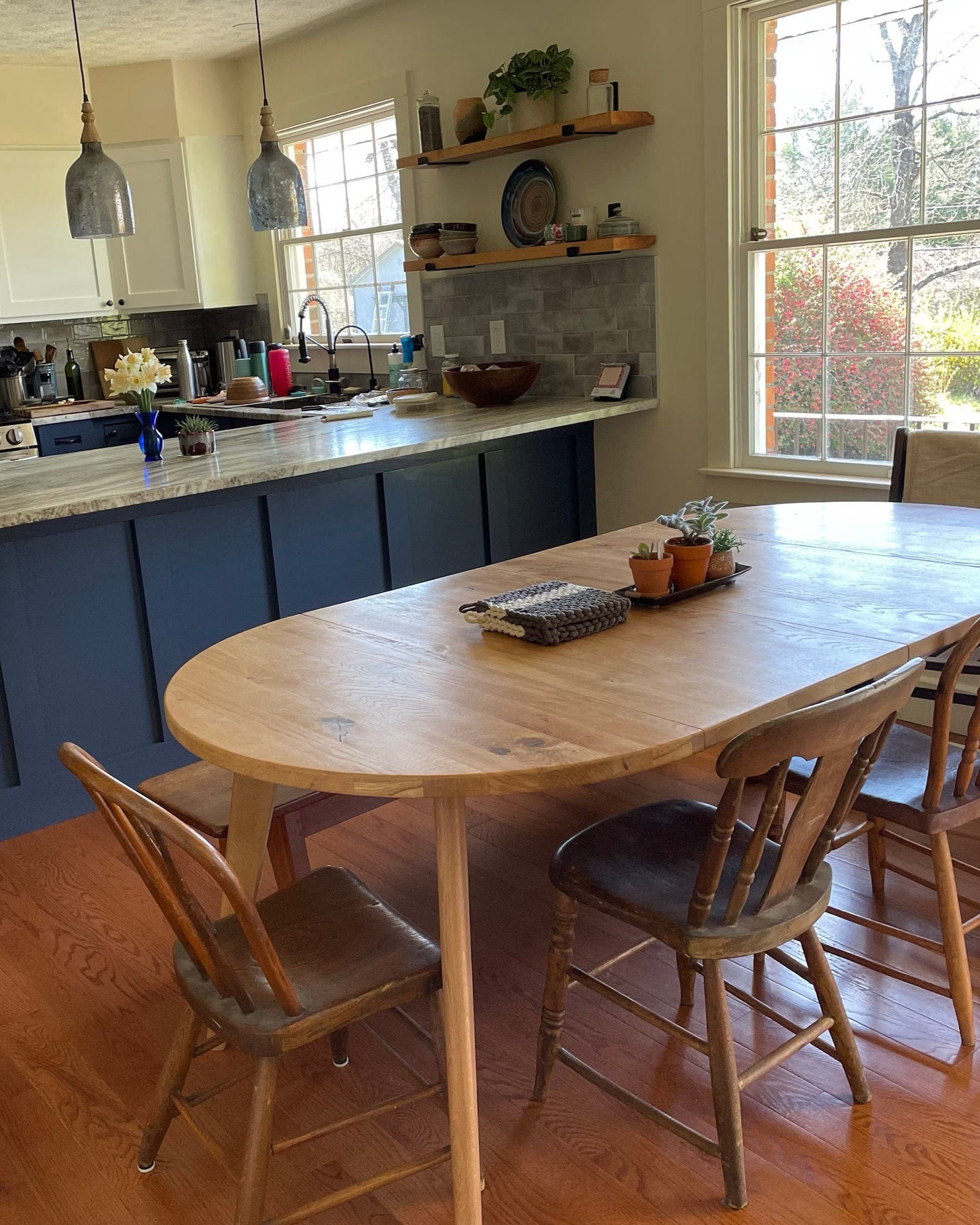 Kitchen with a dining table and chairs, stainless steel appliances, and large windows.