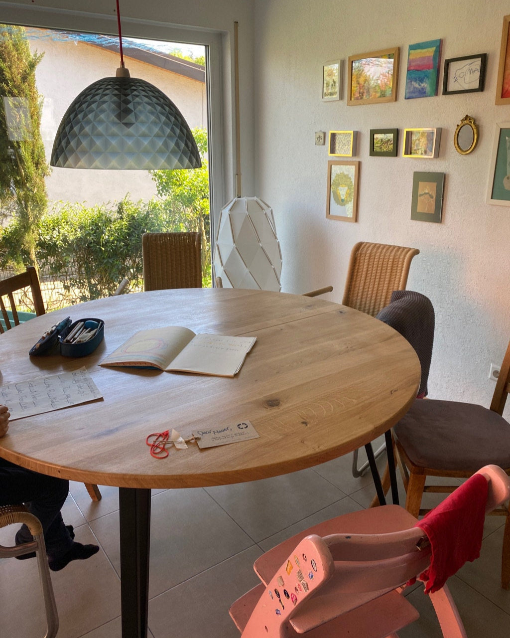 Dining area with a round wooden table and chairs, featuring a window and wall art.